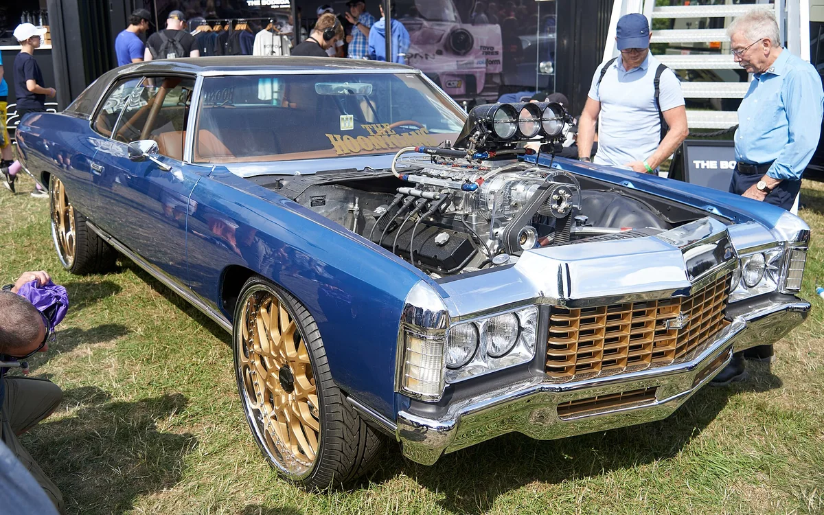 A blue Caprice-style donk on gold wheels at a car show